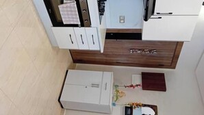 Cocina compacta con armarios blancos, microondas y una pequeña encimera.