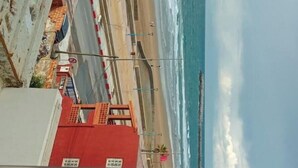 Vista de una playa con un edificio rojo al frente y un cielo despejado.
