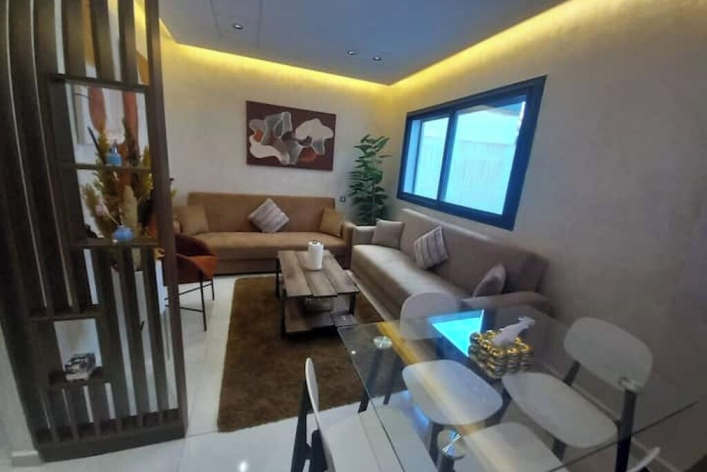 Una sala moderna con un sofá modular, una mesa de centro de vidrio y un comedor con sillas.