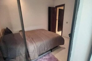 A bedroom with a bed, a door, and a small rug. - Welcome home! (Kénitra)