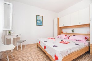 A bedroom with a wooden bed, white walls, a small desk, and a chair. - Apartment Rota (Sveti Filip i Jakov)