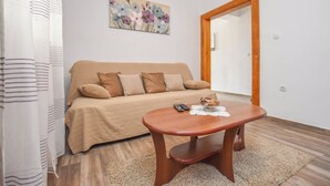 A cozy living room with a beige sofa, a wooden coffee table, and a floral artwork on the wall. - Apartment Rota (Sveti Filip i Jakov)