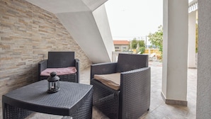 An outdoor seating area with wicker furniture and a lantern, set against a stone wall and a clear view of the surrounding area. - Apartment Rota (Sveti Filip i Jakov)