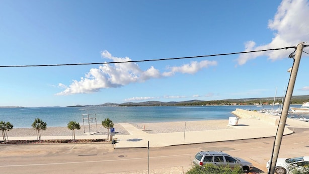 A coastal view with a parking area, a beach, and a marina. - Apartment Rota (Sveti Filip i Jakov)