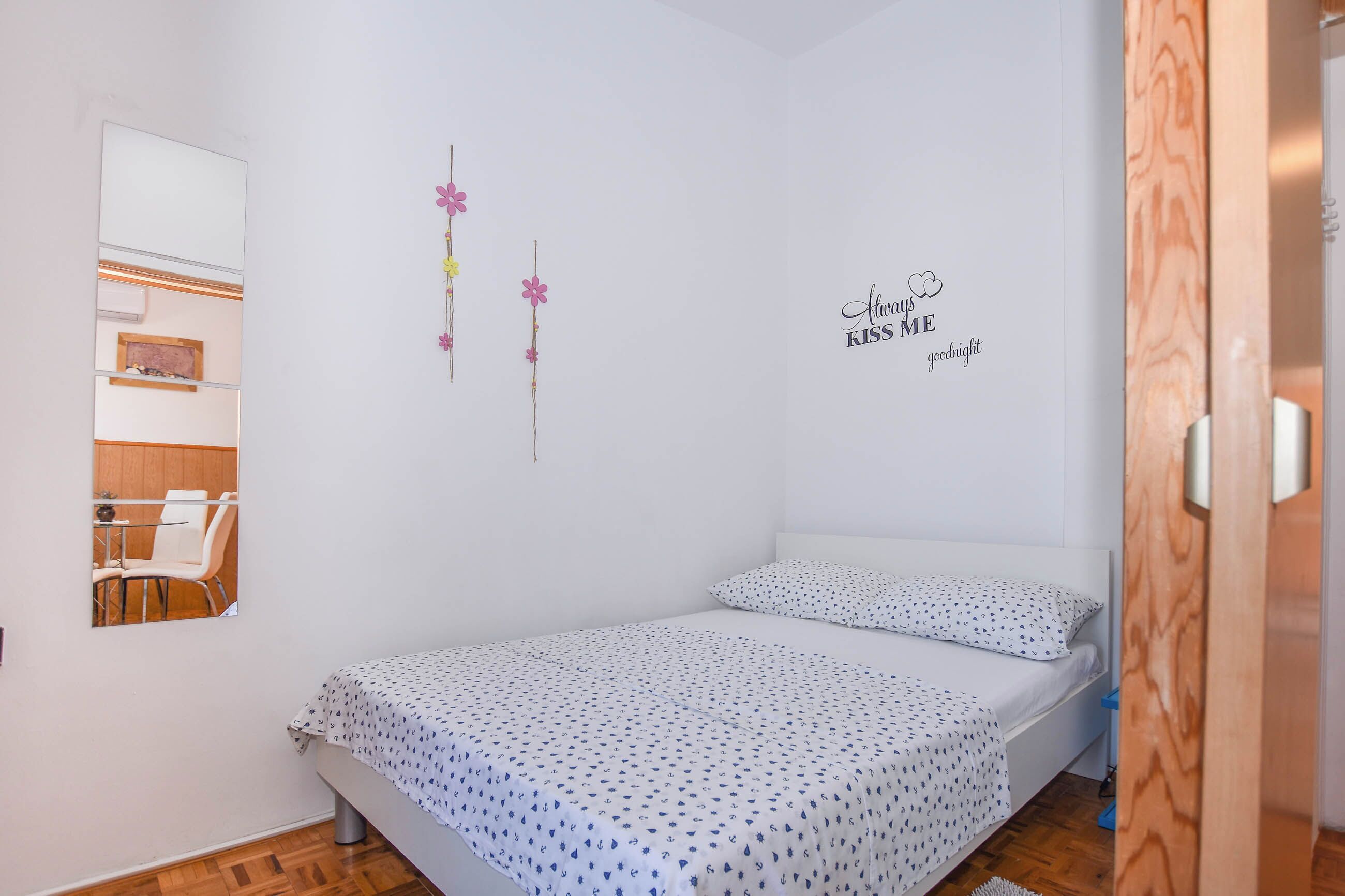 A bedroom with a bed, a mirror, and a wall decoration.