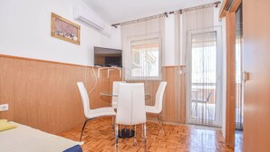 Ein Zimmer mit Bett, Fernseher, Tisch mit St ühlen und einem Fenster mit Vorhängen.