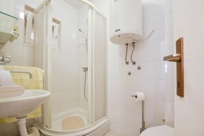 A bathroom with a glass-enclosed shower, a sink, and a toilet. - Apartments Clair (Pag)
