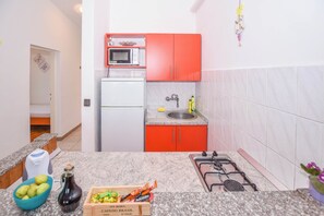 A compact kitchen with a microwave, sink, and gas stove. - Apartments Clair (Pag)