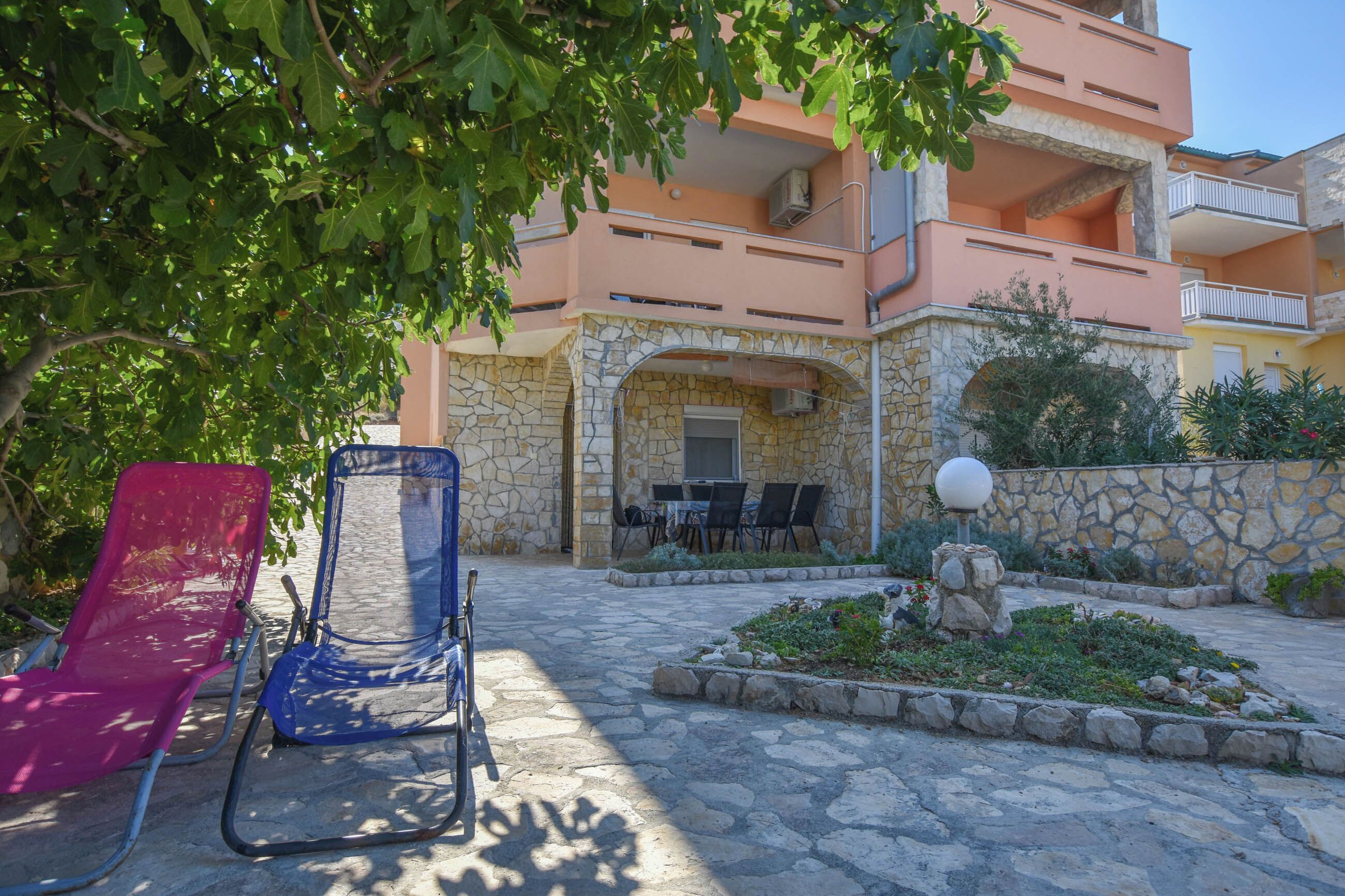 A stone building with a balcony, outdoor seating, and a garden area.