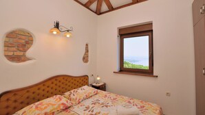 Ein Schlafzimmer mit Bett, Fenster mit Blick, Ziegelwand und Holzboden.