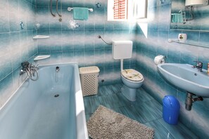 A bathroom with a bathtub, toilet, sink, and blue tiled walls. - House Marko (Pasman)