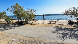 En strand med gyngestativ, bænke og kig til havet.