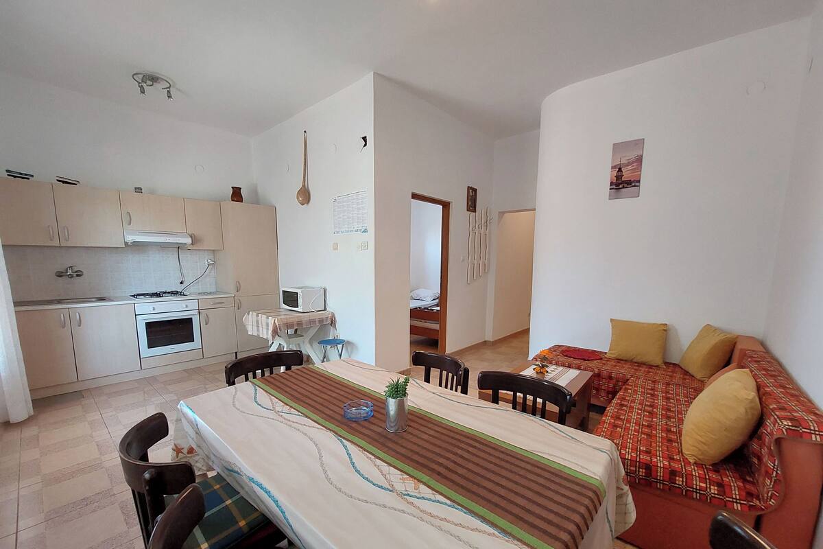 Un espace de vie compact comprenant un coin cuisine, un coin repas et une chambre.