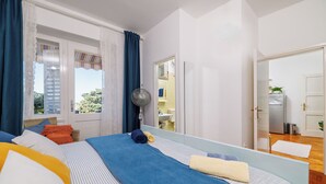 Ein Schlafzimmer mit einem großen Bett, einem Ventilator und Blick ins Badezimmer.