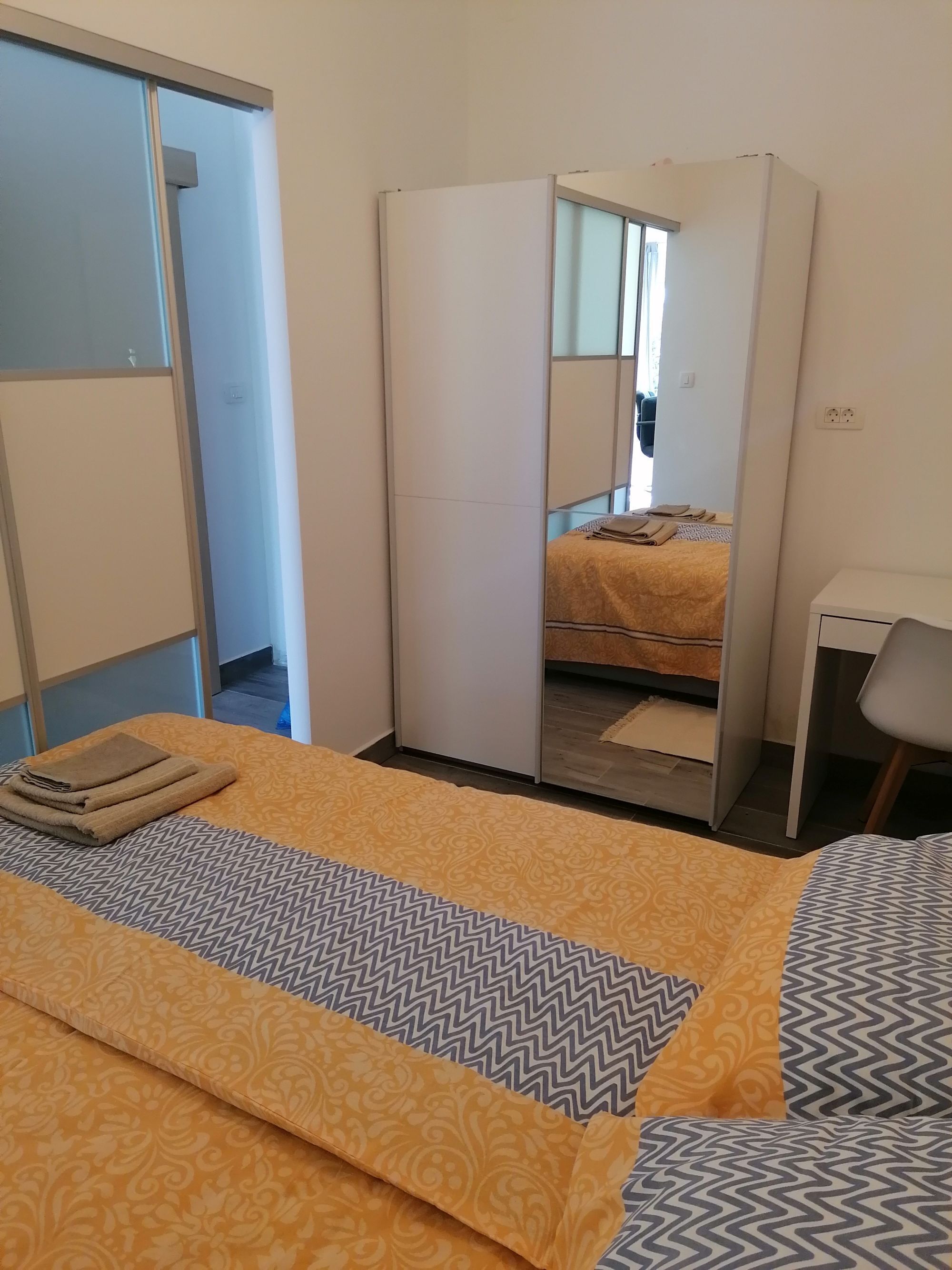 A hotel room with a bed, a wardrobe, a desk, and a chair.