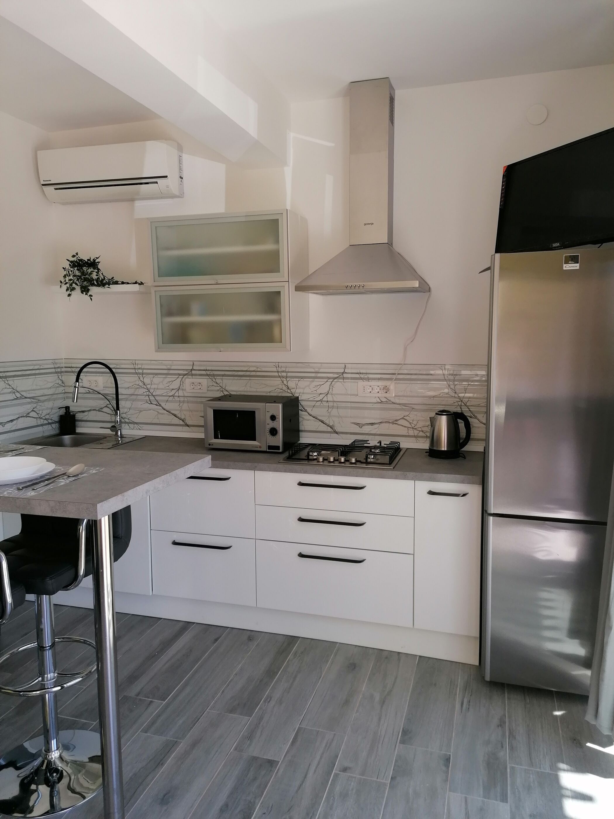 Een moderne keuken met witte kastjes, een roestvrijstalen koelkast, een magnetron en een gasfornuis.