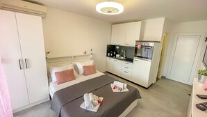 Una habitación de hotel moderna con cama, kitchenette, armario y baño.