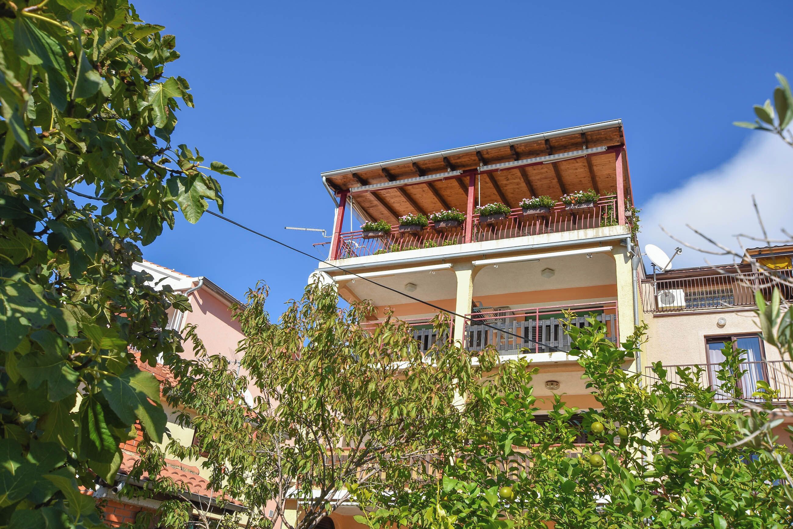 A multi-story building with balconies, some with plants.