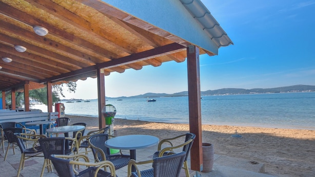 Un área de estar al aire libre con sillas y mesas de mimbre, con vista a una playa y al mar.