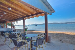 Un espace extérieur aménagé avec des chaises et des tables en osier, offrant une vue sur la plage et la mer.