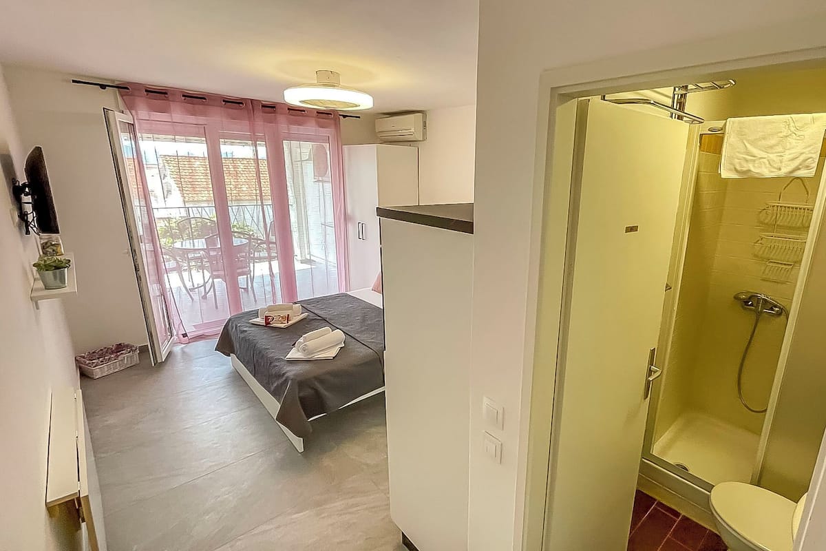 A hotel room with a bed, a shower, and a view of the outside.