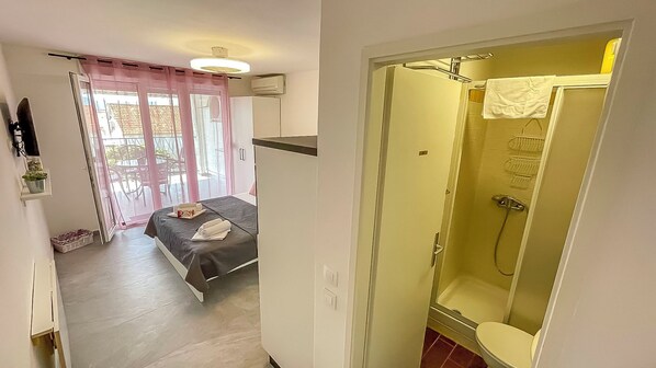 Quarto de hotel com cama, chuveiro e vista para o exterior.