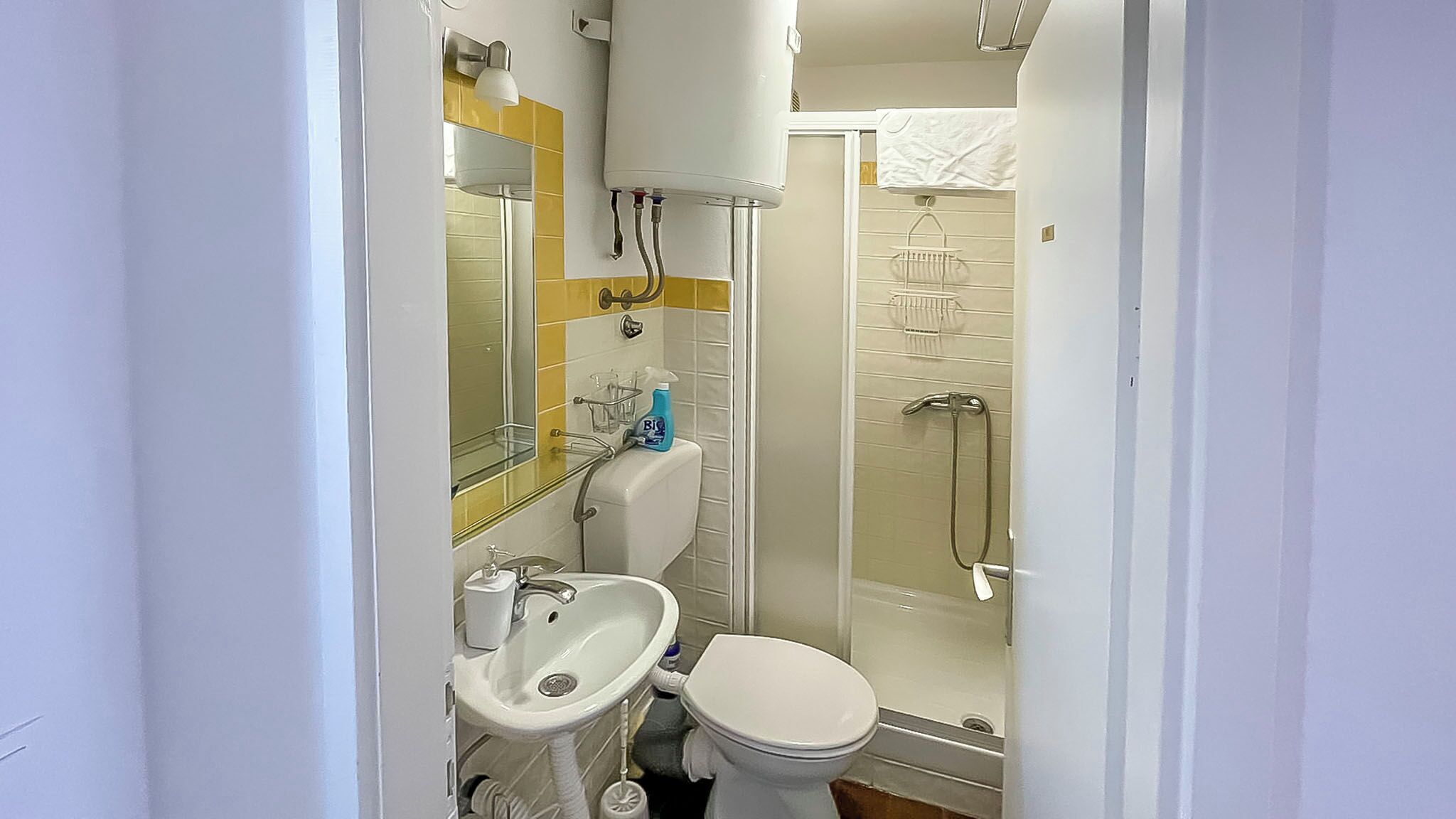 A compact bathroom with a toilet, sink, and shower.