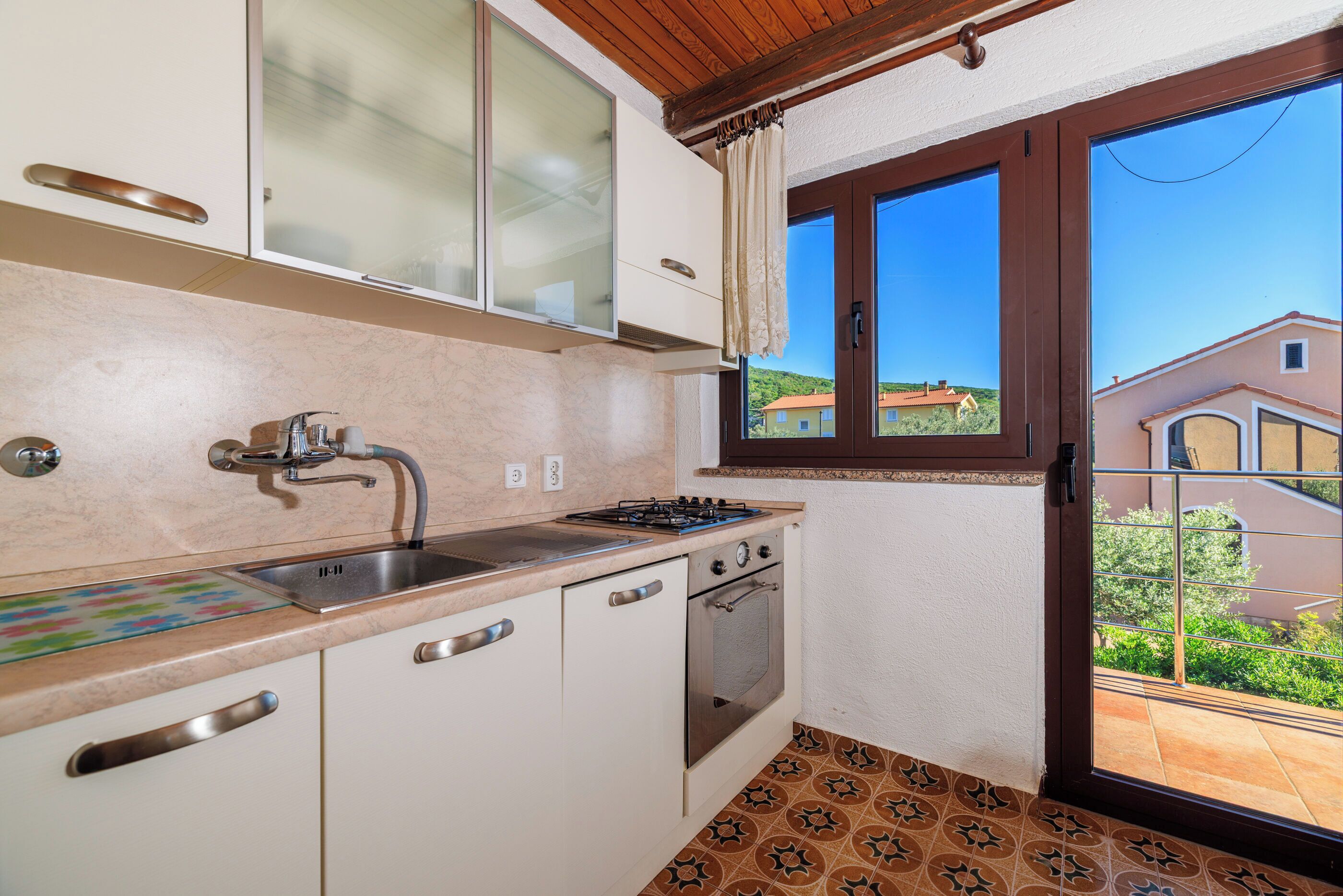 A kitchen with a sink, stove, oven, and cabinets.