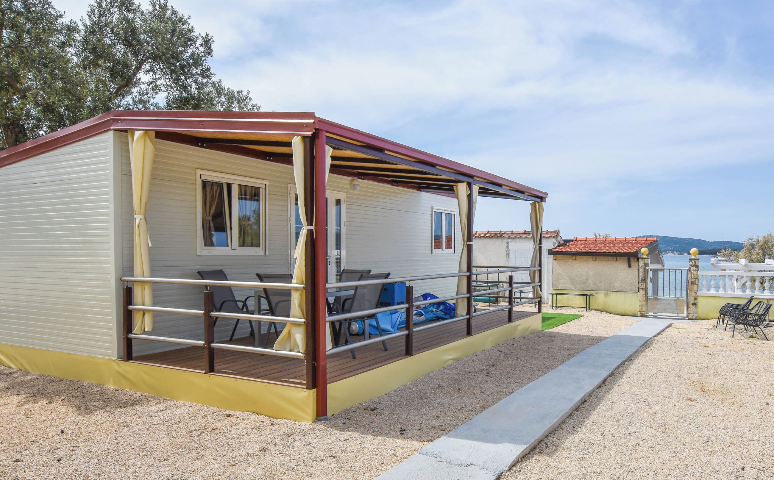 Een stacaravan met een overdekte veranda, zitplaatsen buiten en uitzicht op de omgeving.