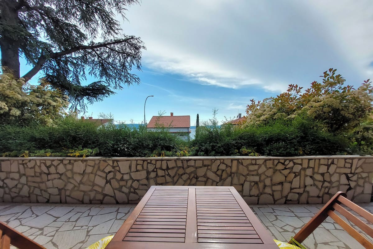 A stone wall with a wooden table and chairs in an outdoor setting.