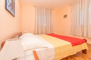 A bed with a red and yellow bedspread, a white pillow, and a white lampshade. - Apartment Island Sun Terrace (Sibenik)