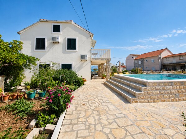 A white building with a stone pool and a stone pathway leading to a staircase. - Apartment Island Sun Terrace (Sibenik)