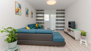 A modern living room with a sofa, a TV, and two potted plants. - Apartment Astrid (Split)