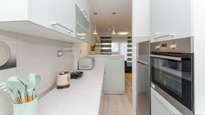 A modern kitchen with white cabinetry, a built-in microwave, a kettle, and a large oven. - Apartment Astrid (Split)
