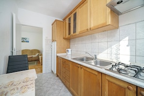 A kitchen with wooden cabinets, a stainless steel sink, and a gas stove. - Apartments Villa Sunset (Vodice)