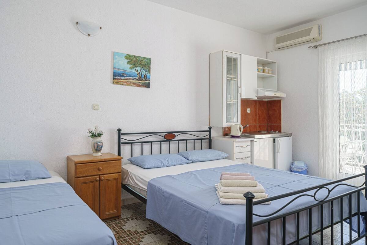 A bedroom with two beds, a wooden nightstand, a cabinet, and a painting on the wall.
