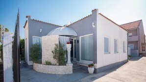 A modern house with a large glass door, a white exterior, and a tiled roof. - House Kala (Sibenik)