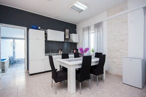 Une cuisine moderne avec des meubles blancs, un plan de travail noir et un coin repas comprenant une table blanche et des chaises noires.