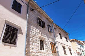 A building with stone facade, multiple windows, and visible electrical wires. - Apartment Rustika Skradin (Skradin)