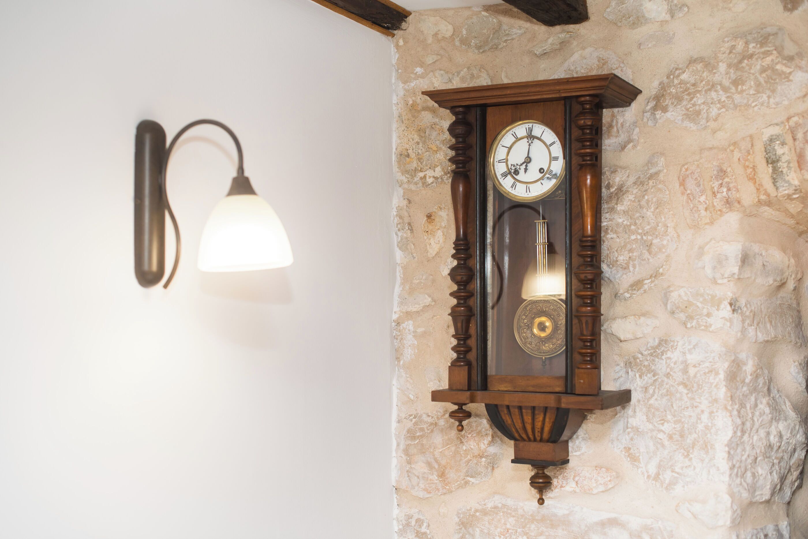 Une horloge murale dotée d’un pendule et d’un luminaire.