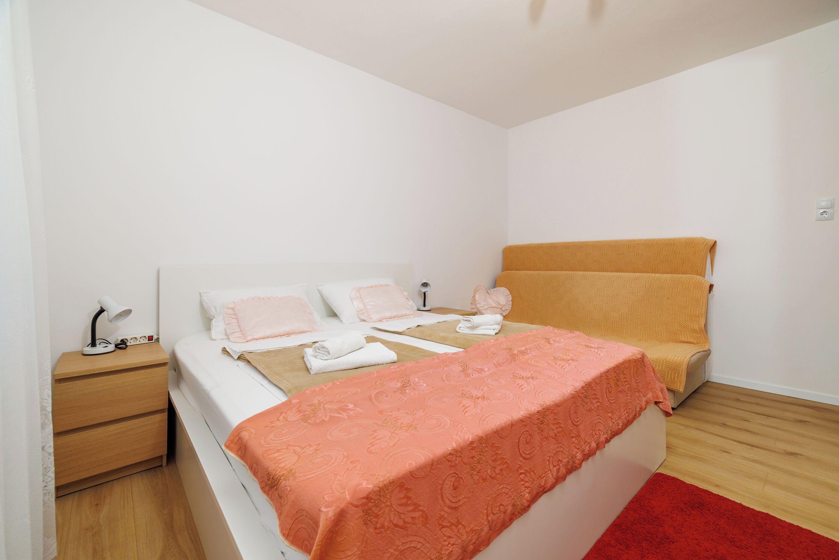 A bedroom with a bed, bedside table, and a chair.