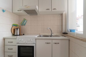 A compact kitchen with a built-in oven, a sink, and cabinets. - Apartments Anamarija (Rovinj)