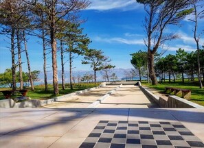 A paved pathway leading to a scenic overlook with a view of mountains and a body of water. - Apartment Tommy (Privlaka)