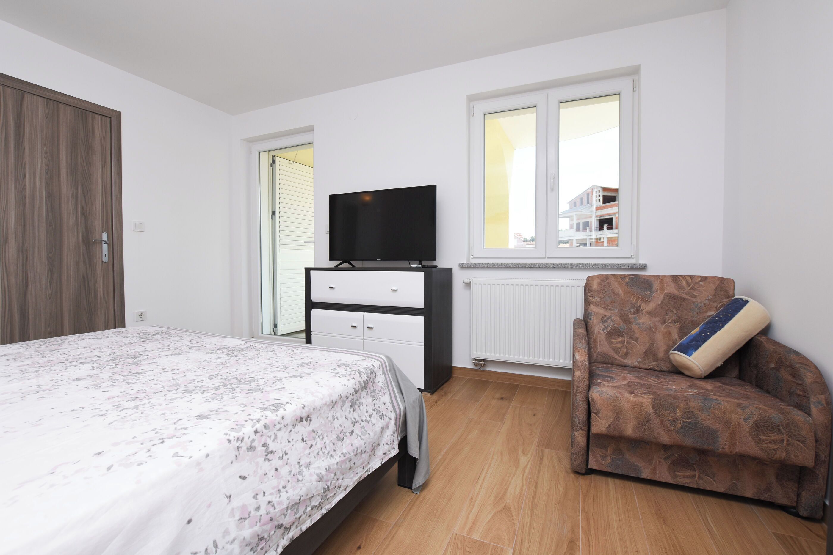 A bedroom with a bed, a dresser, a television, and a window.