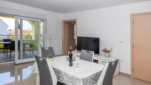 Een moderne eetruimte met een tafel gedekt voor twee personen, een televisie en uitzicht op buiten.