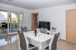 Un comedor moderno con una mesa dispuesta para dos, un televisor y vistas al exterior.