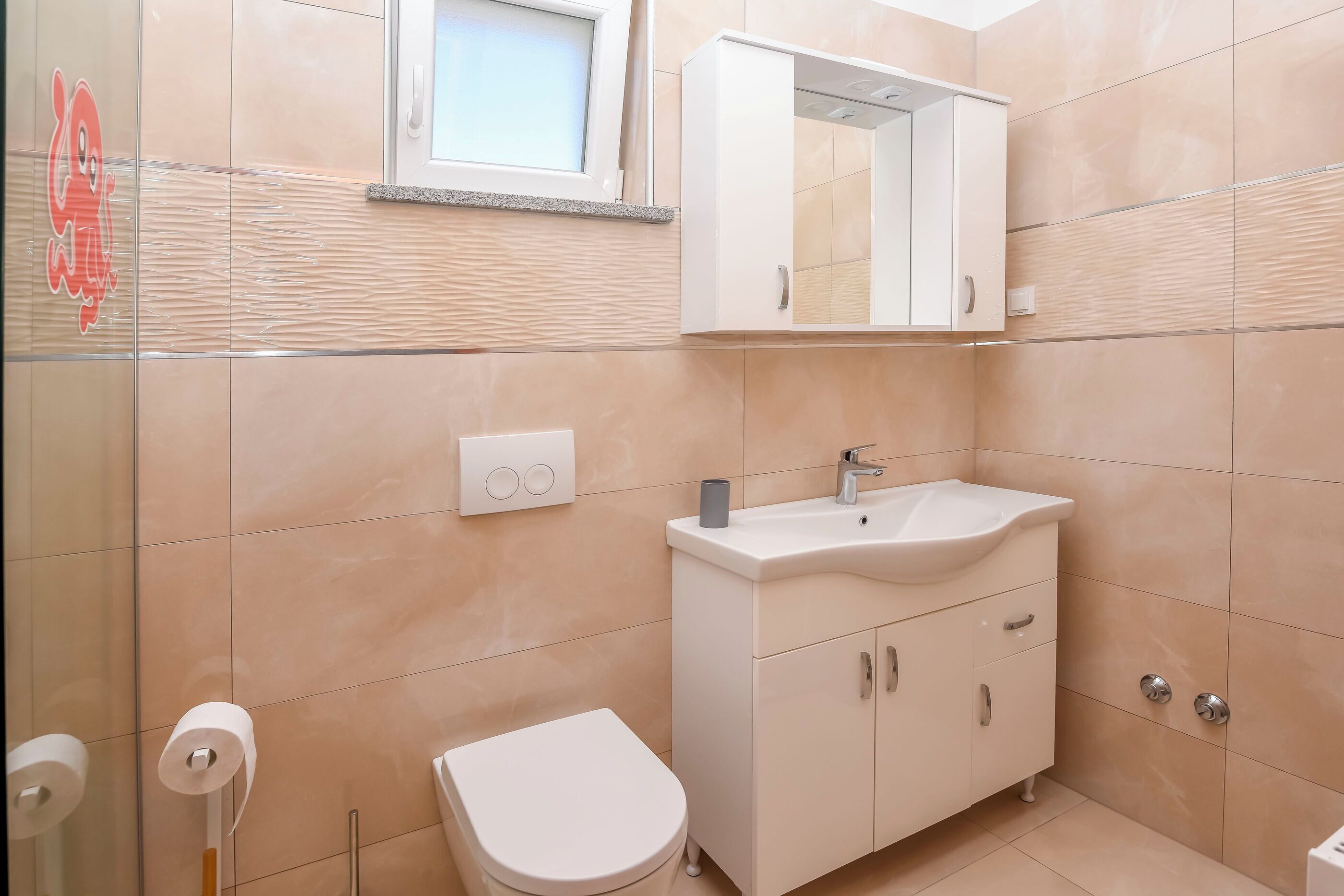 Un baño con inodoro, lavamanos y espejo.