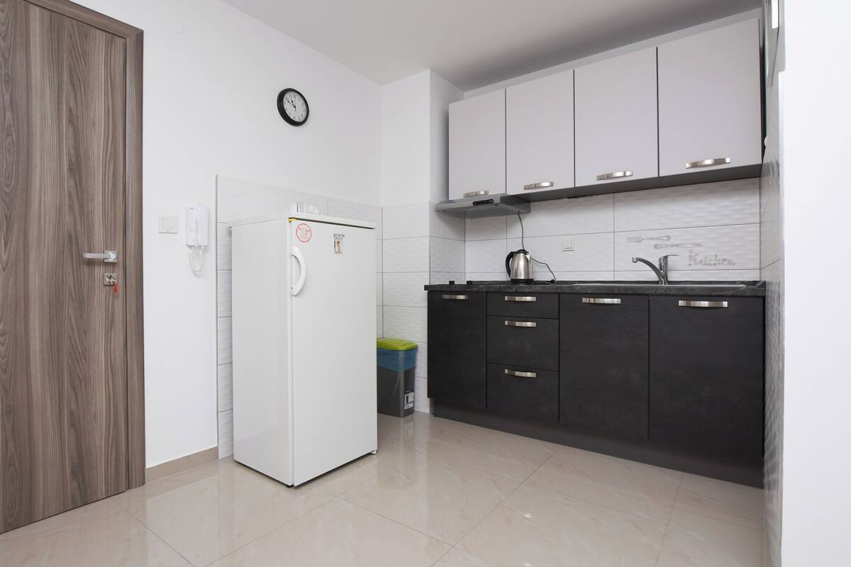 A kitchen with white cabinets, a black countertop, and a white refrigerator.