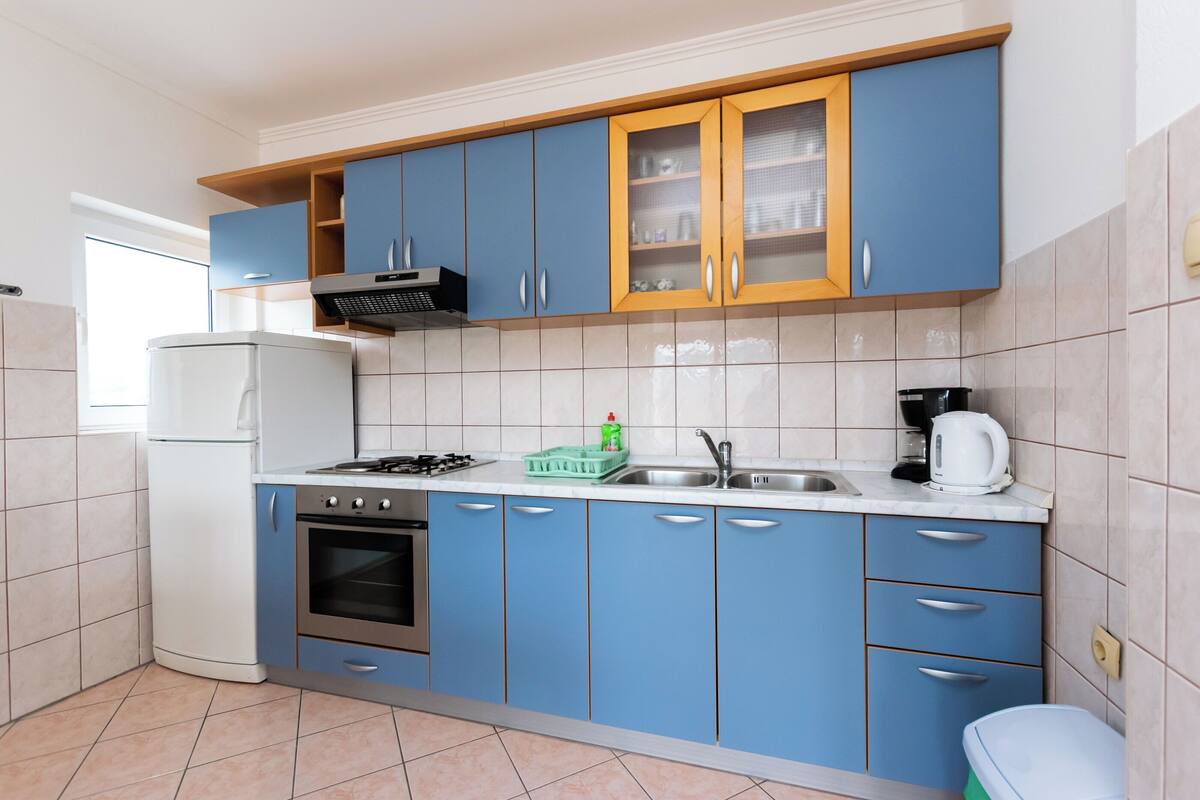 Une cuisine avec des meubles de couleur bleue, un réfrigérateur blanc, une cuisinière et un évier.