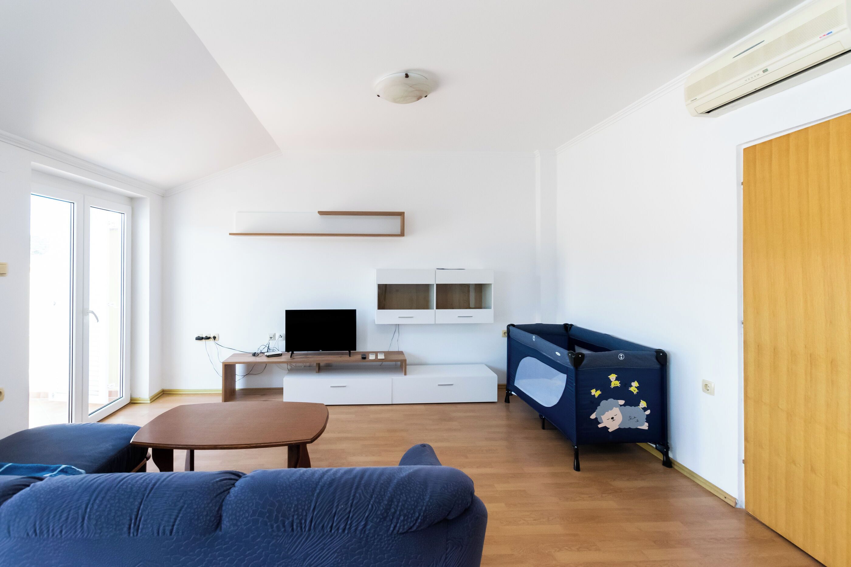 A modern living room with a sofa, a coffee table, a TV, and a blue cabinet with a cartoon character.